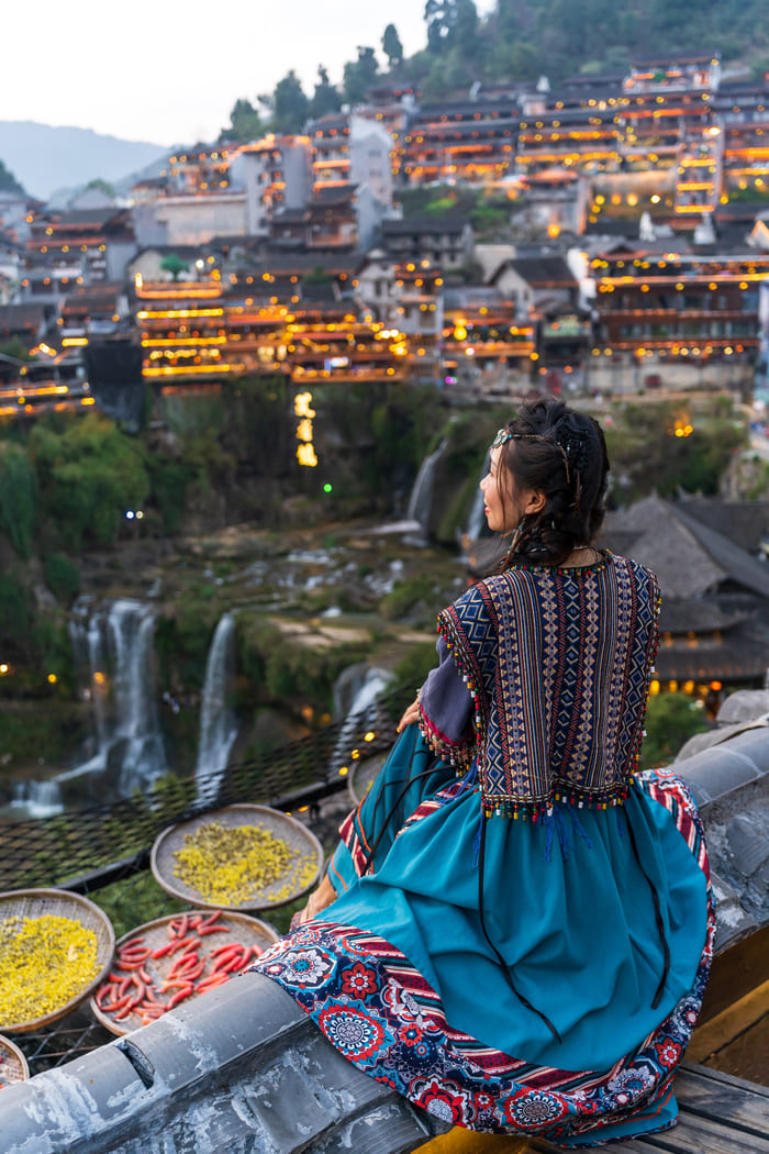 Chica con traje típico Chino admirando el horizonte de la ciudad Lijiang, China.