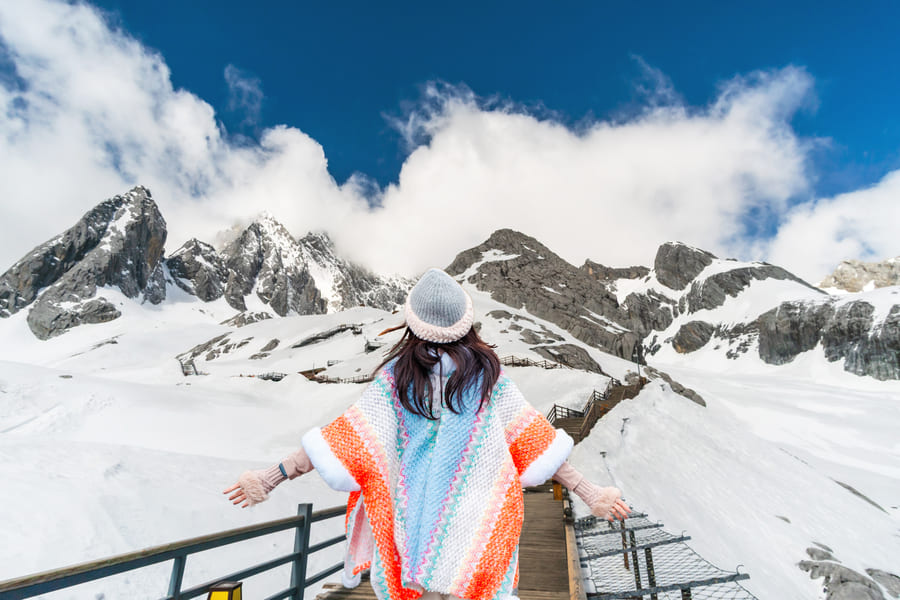 Chica turista caminando en montañas de nieve en Yulongshang, China